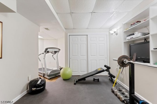 workout room featuring a paneled ceiling, visible vents, and baseboards