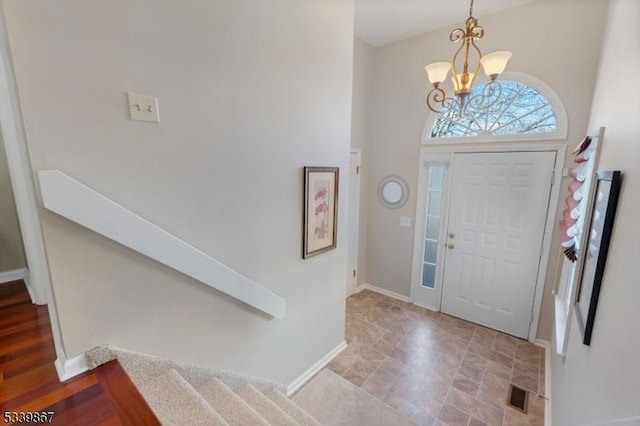 foyer entrance with baseboards, stairway, visible vents, and a notable chandelier