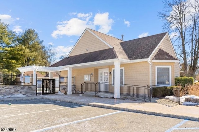 view of front of house featuring a fenced front yard, a gate, a pergola, and roof with shingles