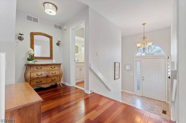 entrance foyer with a chandelier, visible vents, and hardwood / wood-style flooring