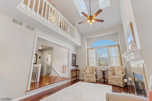 sitting room featuring a high ceiling, visible vents, dark wood finished floors, and a glass covered fireplace