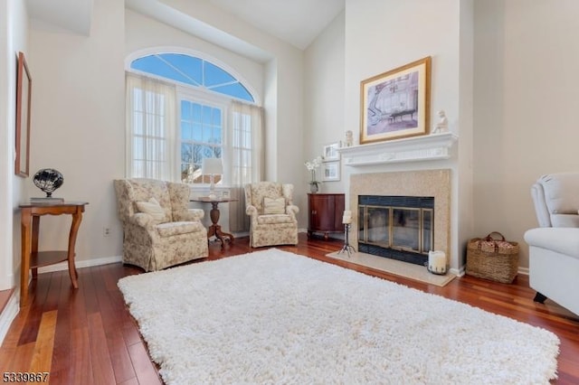 living area featuring a fireplace with flush hearth, dark wood-style flooring, and baseboards