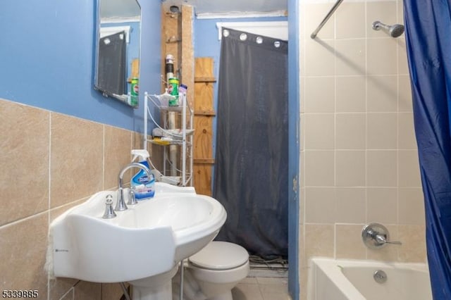 bathroom featuring tile patterned flooring, toilet, shower / tub combo, a sink, and tile walls