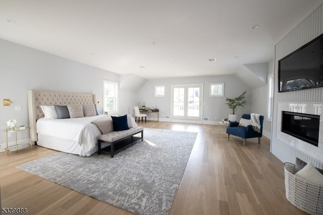 bedroom featuring light wood-type flooring, a fireplace, and baseboards