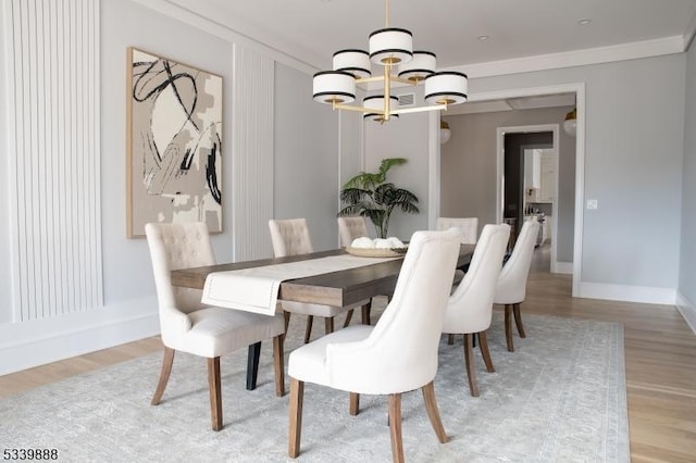 dining space with light wood-style floors, baseboards, a chandelier, and ornamental molding