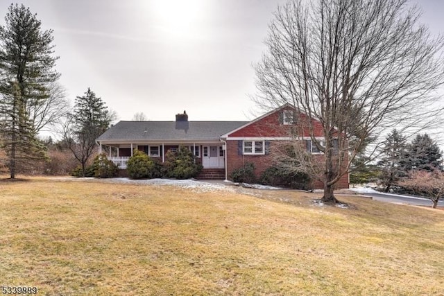 ranch-style house featuring brick siding, a chimney, and a front lawn