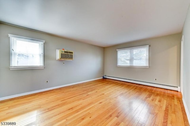 spare room with baseboards, a wall unit AC, hardwood / wood-style floors, and baseboard heating