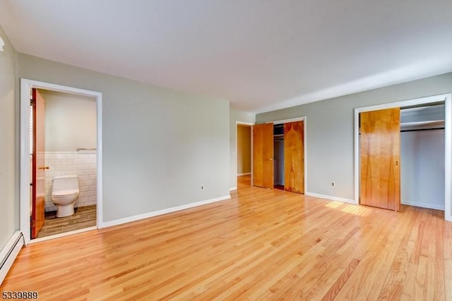 unfurnished bedroom featuring multiple closets, a baseboard radiator, connected bathroom, and light wood finished floors