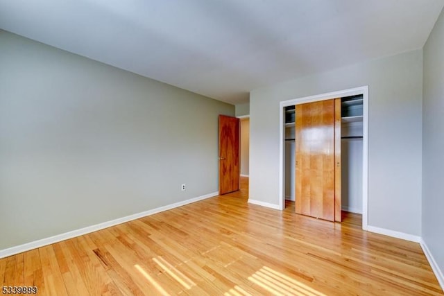 unfurnished bedroom featuring a closet, baseboards, and light wood finished floors