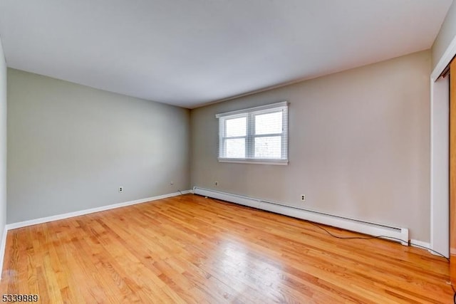 unfurnished room featuring a baseboard radiator, wood finished floors, and baseboards