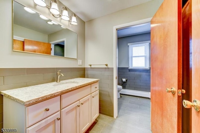 bathroom featuring a wainscoted wall, tile walls, toilet, vanity, and tile patterned flooring