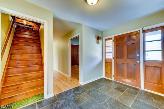 entrance foyer featuring baseboards, stairs, and stone tile floors