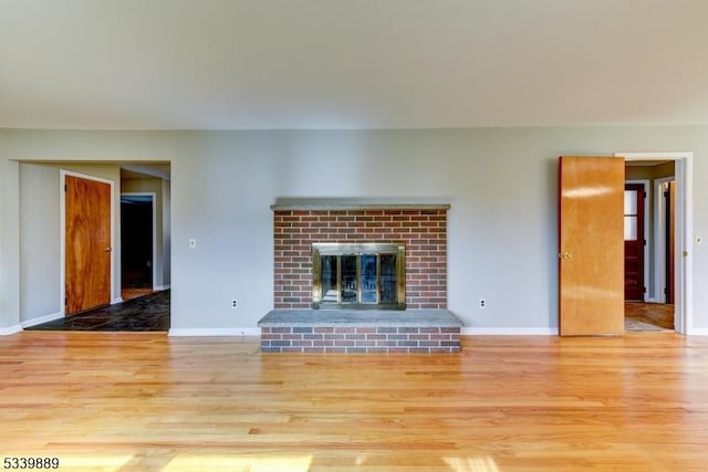 unfurnished living room with light wood-style flooring, a fireplace, and baseboards