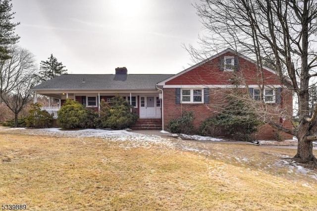 view of front facade with a chimney, a front lawn, and brick siding