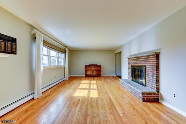 unfurnished living room featuring a baseboard heating unit, a fireplace, baseboards, and wood finished floors