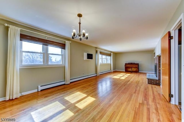 unfurnished living room featuring light wood-style floors, a wall mounted air conditioner, a fireplace, and a notable chandelier