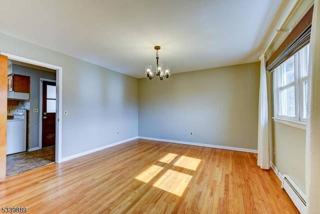 unfurnished room with washer / dryer, a notable chandelier, baseboard heating, and light wood-style floors