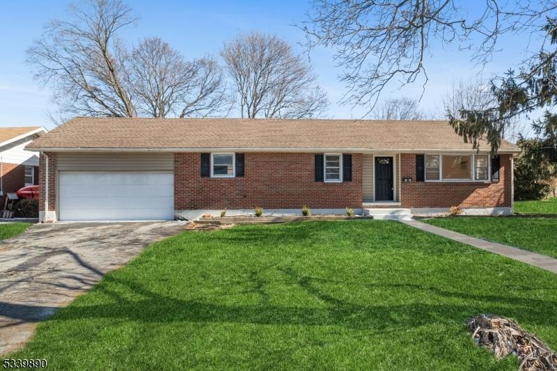 ranch-style house featuring driveway, an attached garage, a front lawn, and brick siding