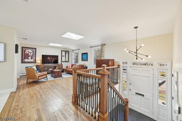 interior space featuring a baseboard heating unit, baseboards, vaulted ceiling, wood finished floors, and a notable chandelier