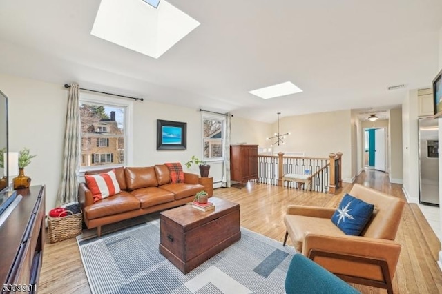 living room with light wood finished floors, visible vents, and a skylight