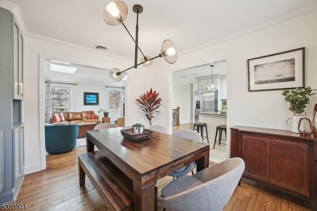 dining area with visible vents, wood finished floors, and ornamental molding