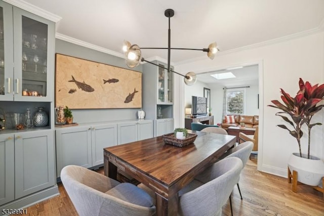 dining room with a skylight, light wood-style flooring, and crown molding