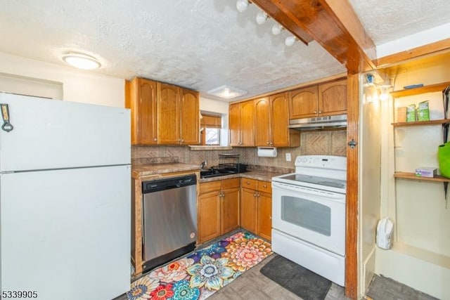 kitchen with tasteful backsplash, white appliances, a sink, and under cabinet range hood