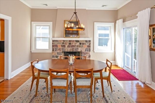 dining space with ornamental molding, a fireplace, wood finished floors, and visible vents