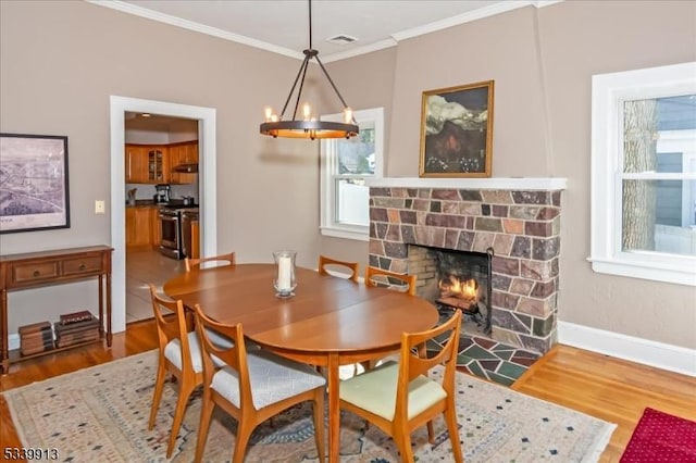 dining area with a fireplace with flush hearth, a wealth of natural light, crown molding, and wood finished floors