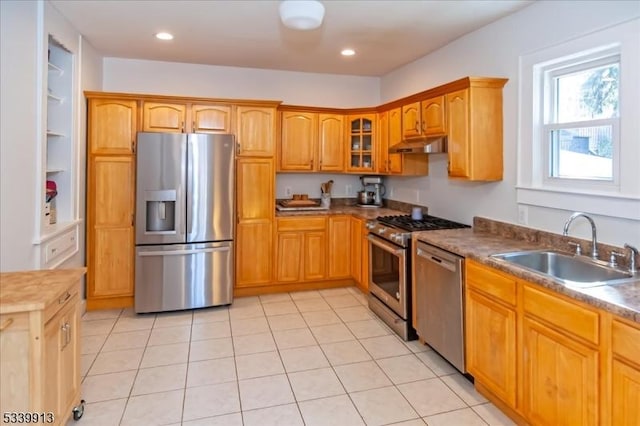 kitchen featuring glass insert cabinets, appliances with stainless steel finishes, under cabinet range hood, a sink, and recessed lighting