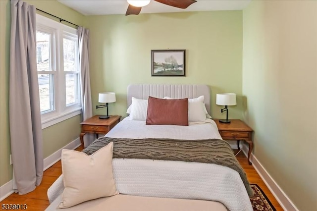 bedroom featuring a ceiling fan, baseboards, and wood finished floors