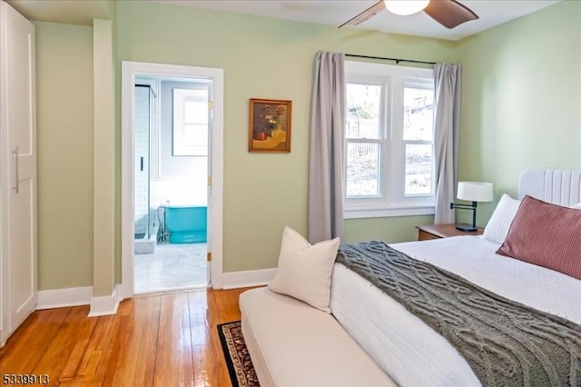 bedroom featuring ensuite bathroom, multiple windows, light wood-type flooring, and baseboards