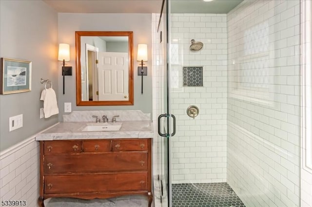 full bath featuring wainscoting, a shower stall, and vanity