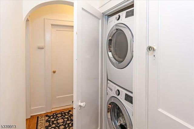 washroom featuring laundry area, stacked washer / drying machine, and wood finished floors