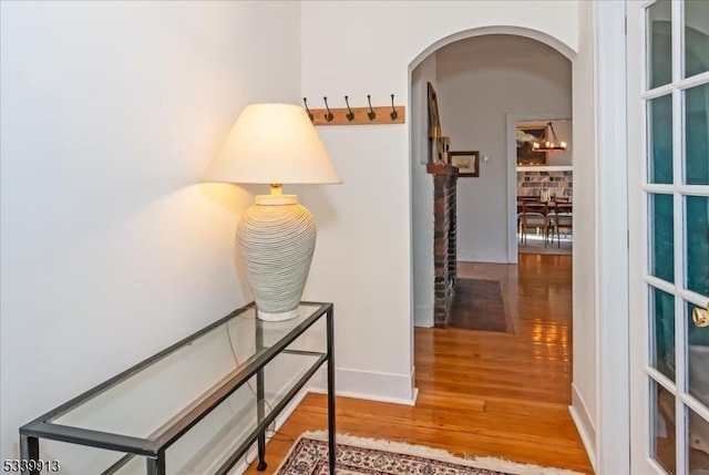 hallway with baseboards, arched walkways, and wood finished floors