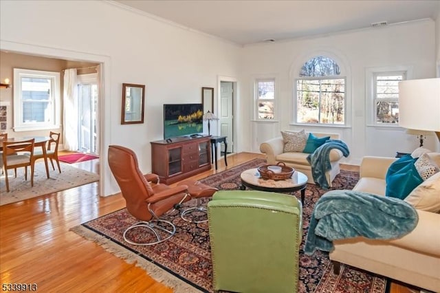 living area with visible vents, a wealth of natural light, and wood finished floors