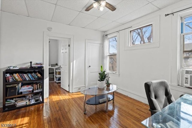 office space with hardwood / wood-style floors, a drop ceiling, a ceiling fan, and a healthy amount of sunlight