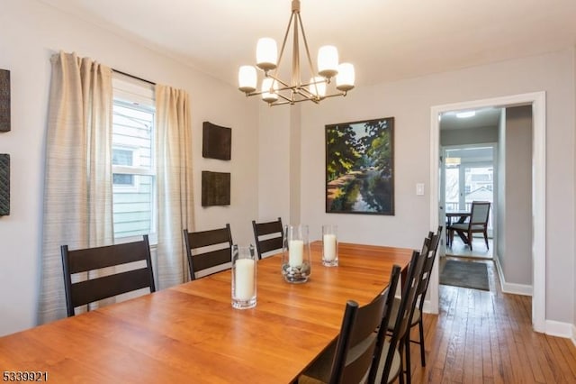 dining space with a notable chandelier, baseboards, and hardwood / wood-style flooring