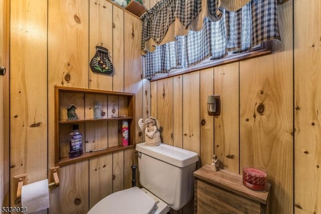 bathroom with toilet and wood walls