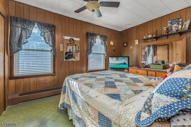 bedroom with a ceiling fan, carpet, wood walls, and baseboard heating