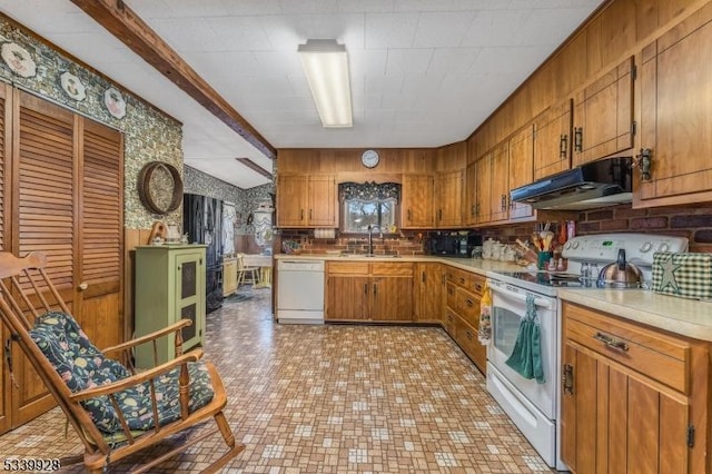 kitchen with white appliances, brown cabinetry, light countertops, under cabinet range hood, and a sink