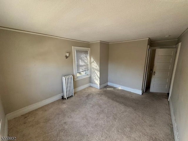 empty room with a textured ceiling, light colored carpet, baseboards, radiator, and crown molding