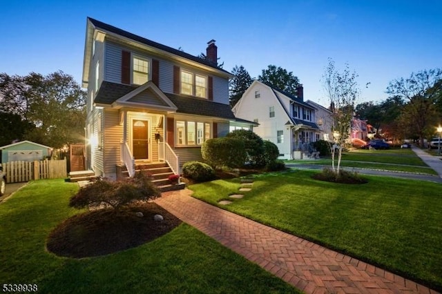 view of front of property with entry steps, fence, and a front yard