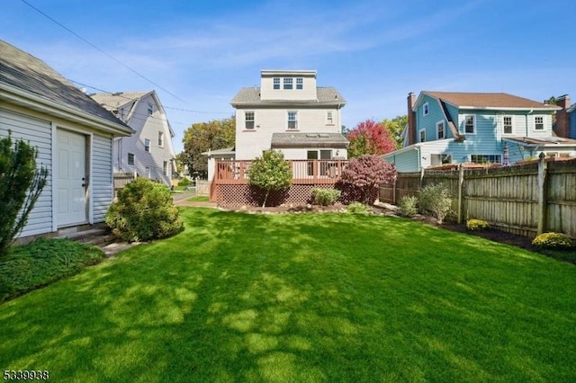 back of house featuring a residential view, a lawn, a wooden deck, and fence