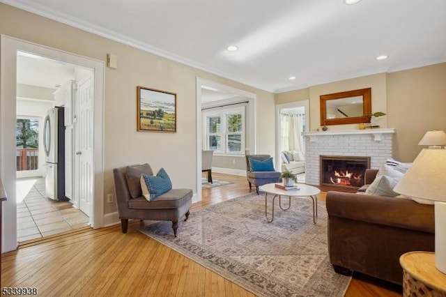 living room featuring crown molding, light wood-type flooring, a fireplace, and plenty of natural light