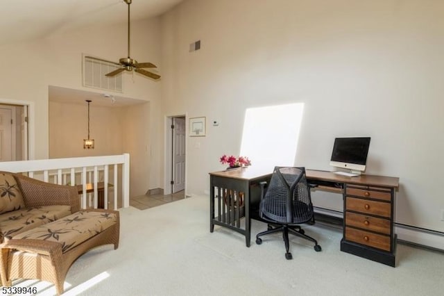 office area with high vaulted ceiling, visible vents, light carpet, and baseboard heating