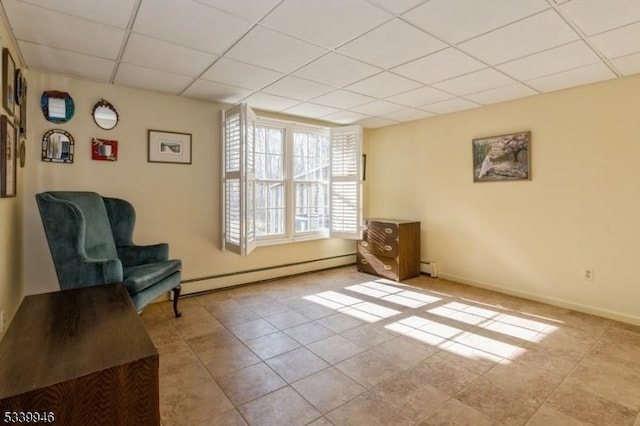 living area with a paneled ceiling, a baseboard radiator, baseboards, and light tile patterned flooring