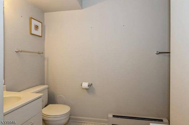 half bath featuring baseboard heating, vanity, toilet, and baseboards