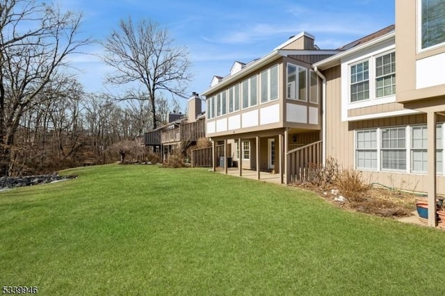 rear view of house featuring a sunroom and a lawn