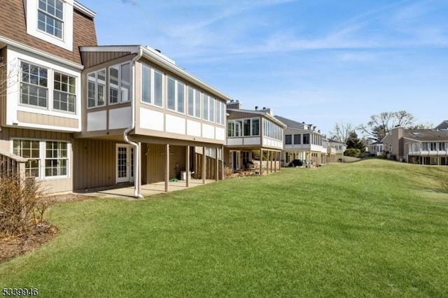 back of house featuring a residential view, a lawn, and a patio